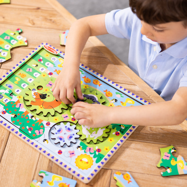 A kid playing with The Melissa & Doug Wooden Animal Chase Jigsaw Spinning Gear Puzzle – 24 Pieces