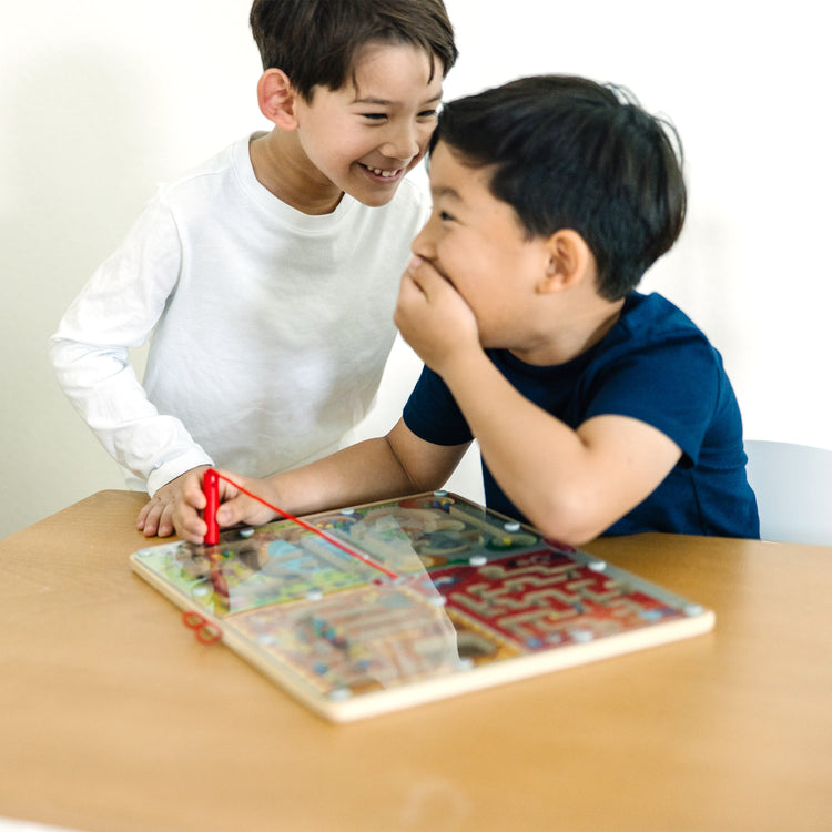 A kid playing with The Melissa & Doug PAW Patrol Wooden 4-in-1 Magnetic Wand Maze Board