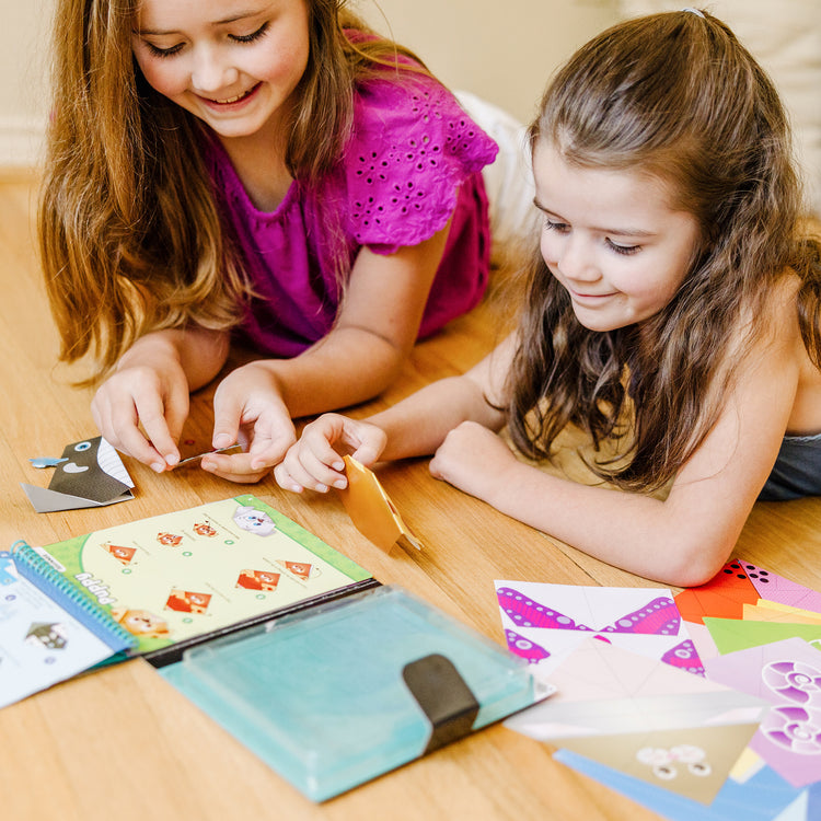 A kid playing with The Melissa & Doug On the Go Origami Animals Craft Activity Set - 38 Stickers, 40 Origami Papers