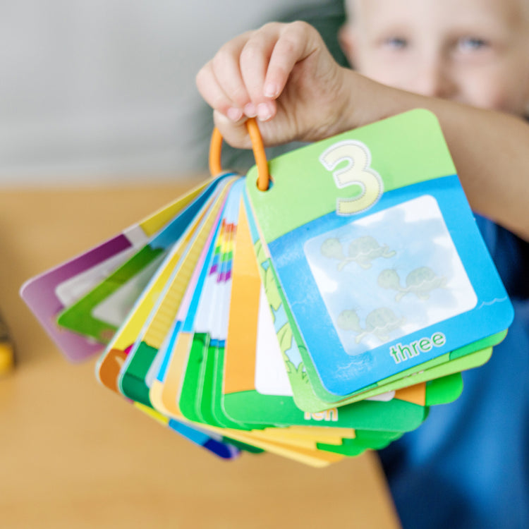 A kid playing with The Doug On the Go Water Wow! Reusable Water-Reveal Cards - Shapes, Numbers, Colors