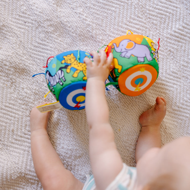 A kid playing with The Melissa & Doug K's Kids Bongo Drums Soft Musical Instrument