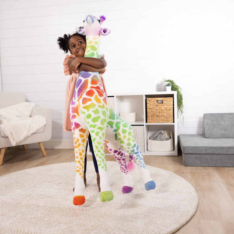 A kid playing with The Melissa & Doug Rainbow Giraffe Lifelike Plush