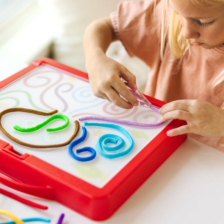 A kid playing with The Melissa & Doug Rainbow Cord Picture And Pattern Maker Draw with Cords Activity – 39 Cords, 6 Double-Sided Cards to Trace