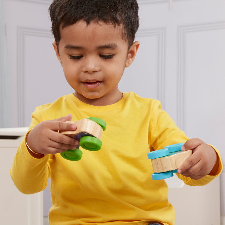 A kid playing with The Melissa & Doug First Play Wooden Animal Stacking Cars (3 pcs)