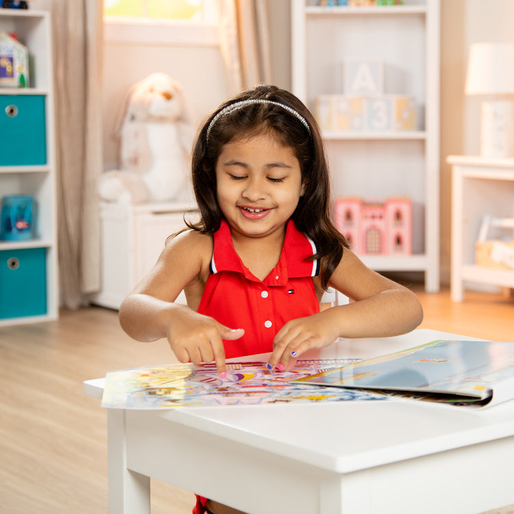 A kid playing with The Melissa & Doug Reusable Sticker Pad: Vehicles - 165+ Reusable Stickers