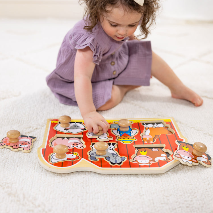 A kid playing with The Melissa & Doug Farm Animals Jumbo Knob Wooden Puzzle