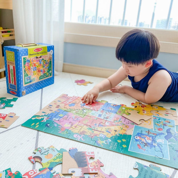 A kid playing with The Melissa & Doug Natural Play Giant Floor Puzzle: America the Beautiful (60 Pieces)