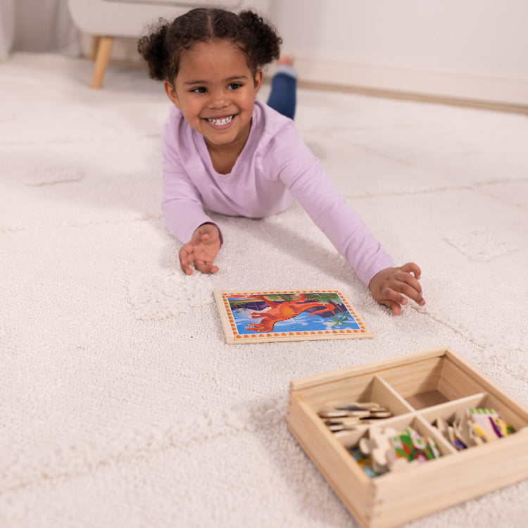 A kid playing with The Melissa & Doug Dinosaurs 4-in-1 Wooden Jigsaw Puzzles in a Storage Box (48 pcs)