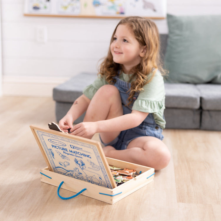 A kid playing with The Melissa & Doug National Parks Wooden Picture Matching Magnetic Game