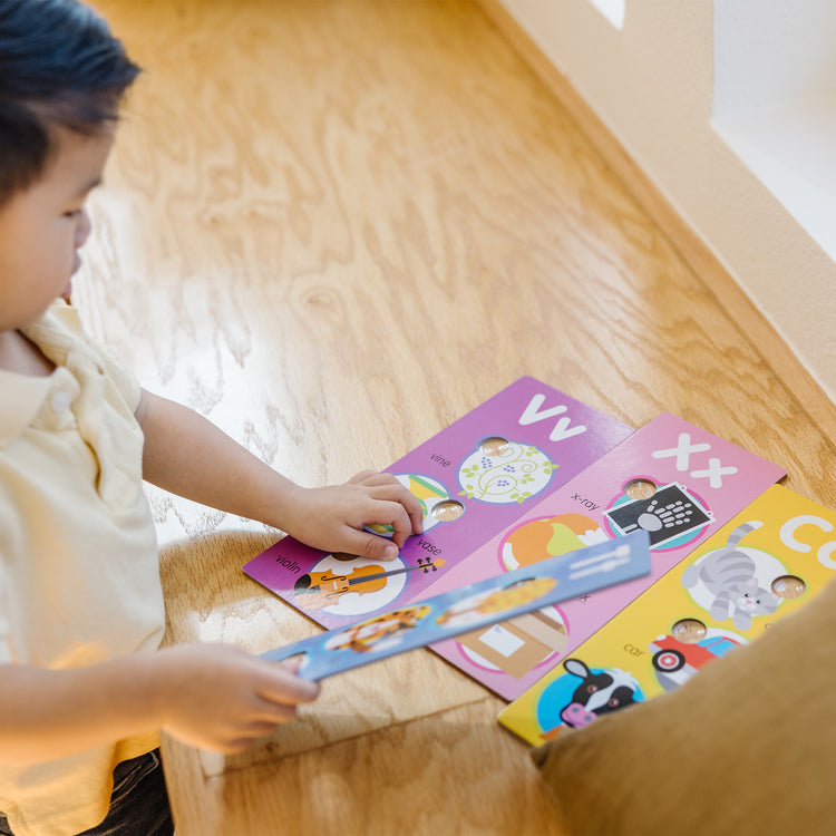 A kid playing with The Melissa & Doug Poke-a-Dot Alphabet Learning Cards