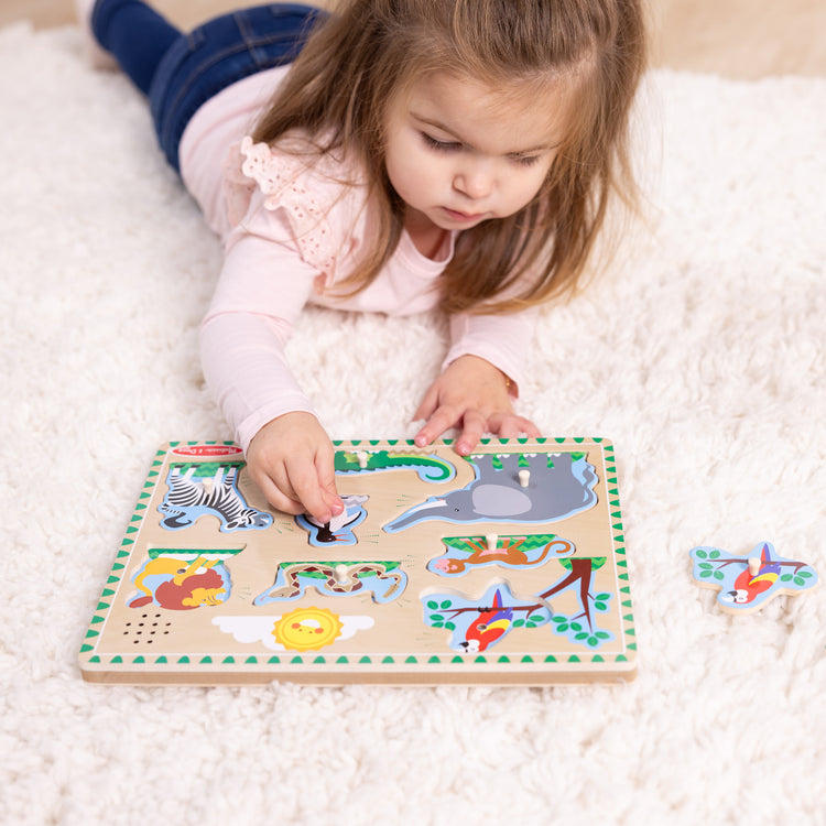 A kid playing with The Melissa & Doug Zoo Animals Sound Puzzle - Wooden Peg Puzzle With Sound Effects (8 pcs)