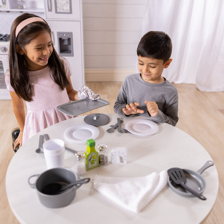 A kid playing with The Melissa & Doug 22-Piece Play Kitchen Accessories Set - Utensils, Pot, Pans, and More