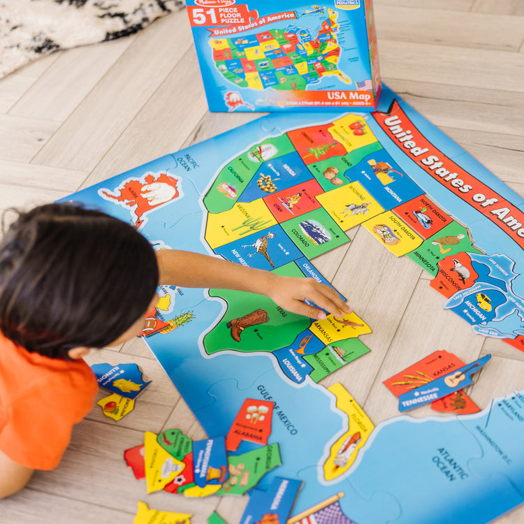 A kid playing with The Melissa & Doug USA Map Floor Puzzle - 51 Pieces (2 x 3 feet)