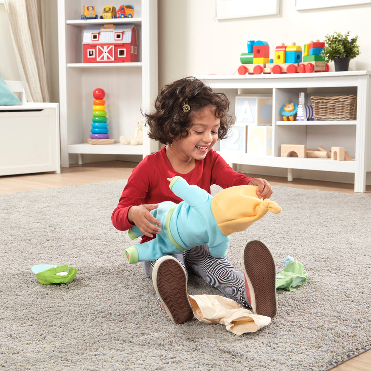 A kid playing with The Melissa & Doug Mine to Love Mix & Match Playtime Doll Clothes for 12”-18” Unisex Dolls (6 pcs)