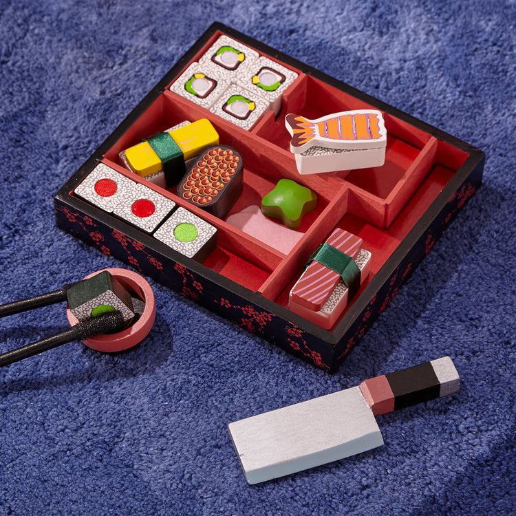 A kid playing with The Melissa & Doug Sushi Slicing Wooden Play Food Set