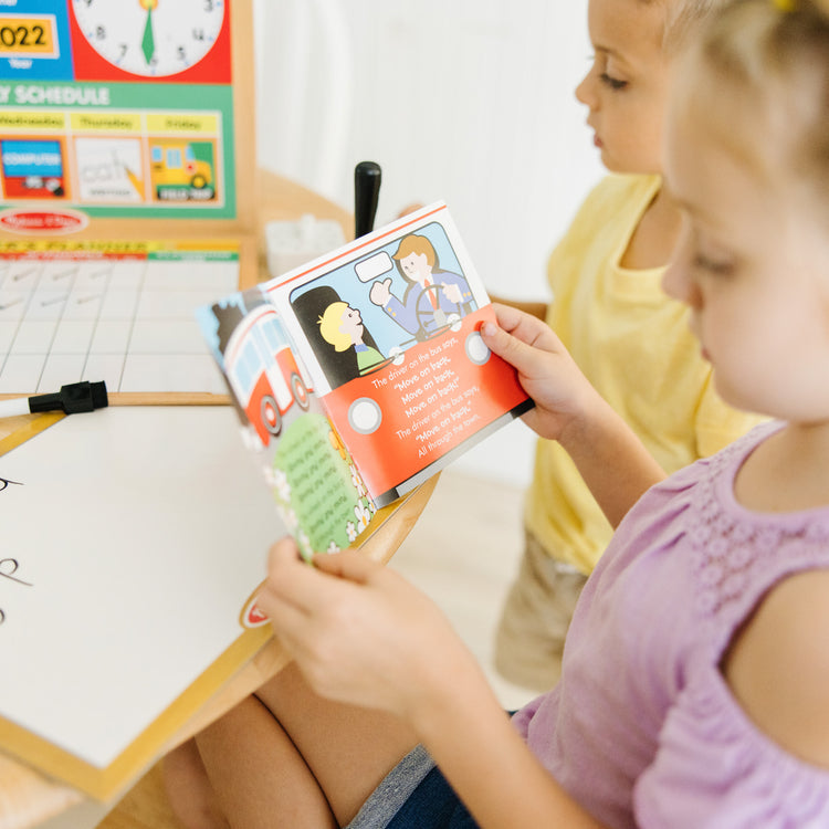 A kid playing with The Melissa & Doug School Time! Classroom Play Set Game - Be Teacher or Student