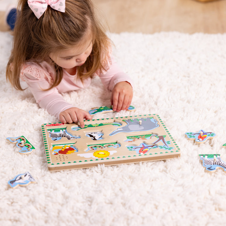 A kid playing with The Melissa & Doug Zoo Animals Sound Puzzle - Wooden Peg Puzzle With Sound Effects (8 pcs)