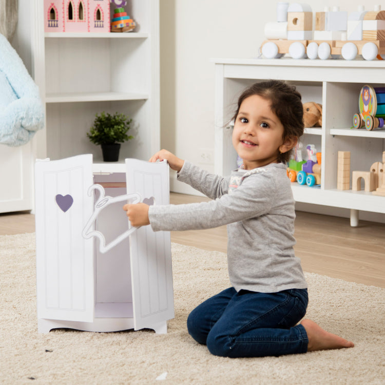 A kid playing with The Melissa & Doug Mine to Love Wooden Play Armoire Closet for Dolls, Stuffed Animals - White (17.3”H x 12.4”W x 8.5”D Assembled)