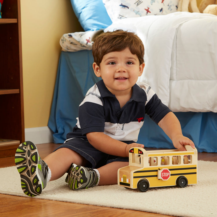 A kid playing with The Melissa & Doug School Bus Wooden Play Set With 7 Play Figures