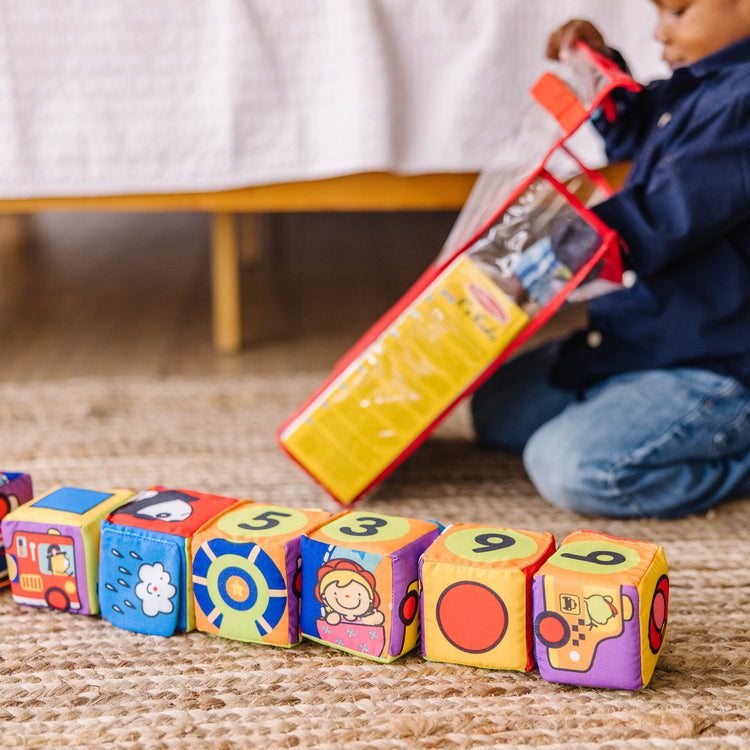 A kid playing with The Melissa & Doug K's Kids Match and Build Soft Blocks Set