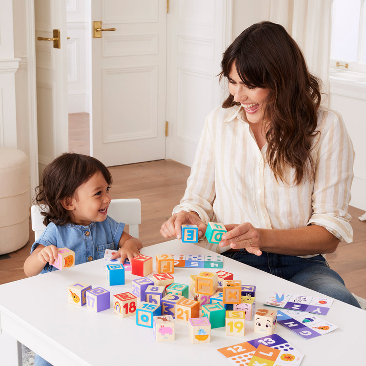 A kid playing with The Melissa & Doug Ms. Rachel Letter, Number, and Game Wooden Learning Blocks with Activity Cards for Girls and Boys Toddlers Ages 18 Months+