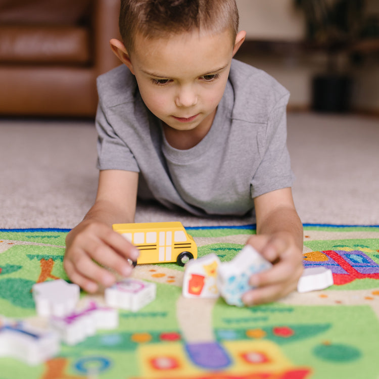 A kid playing with The Melissa & Doug Blue's Clues & You! Blue's Neighborhood Activity Rug (44 Inches x 26 Inches Rug, 9 Wooden Play Pieces)