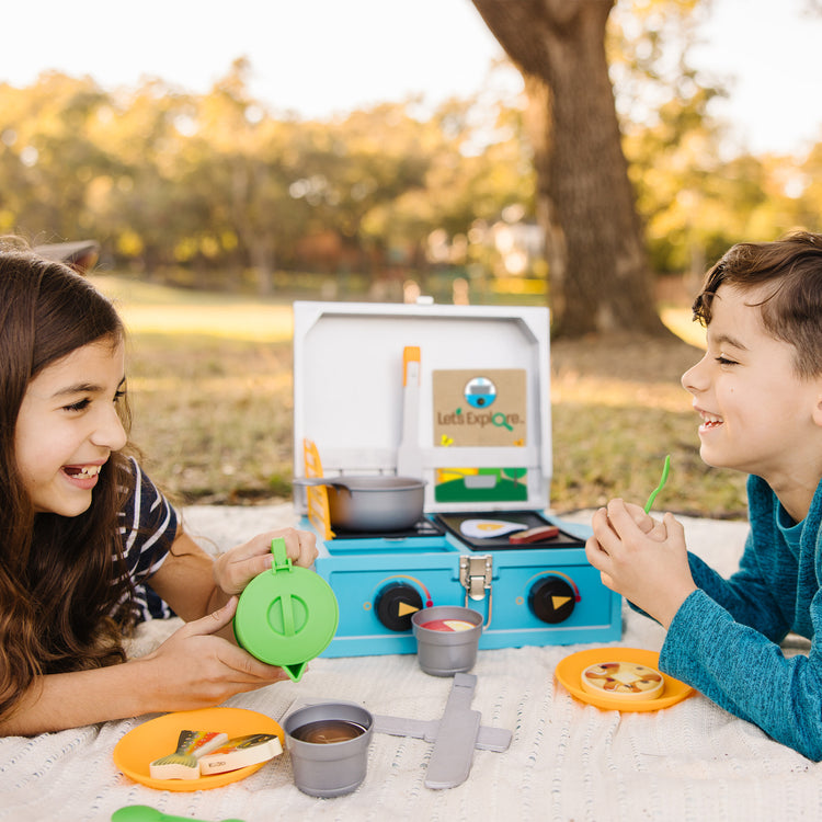 A kid playing with The Melissa & Doug Let’s Explore Camp Stove Play Set – 24 Pieces