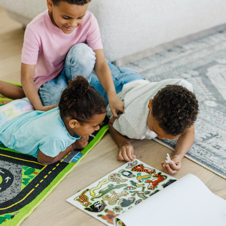 A kid playing with The Melissa & Doug Reusable Sticker Pad: Habitats - 150+ Reusable Stickers