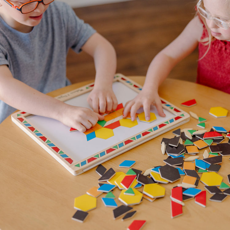 A kid playing with The Melissa & Doug Deluxe Wooden Magnetic Pattern Blocks Set - Educational Toy With 120 Magnets and Carrying Case