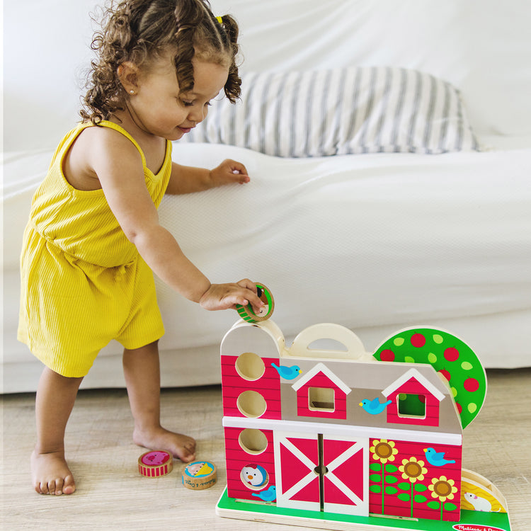 A kid playing with The Melissa & Doug GO Tots Wooden Barnyard Tumble with 4 Disks