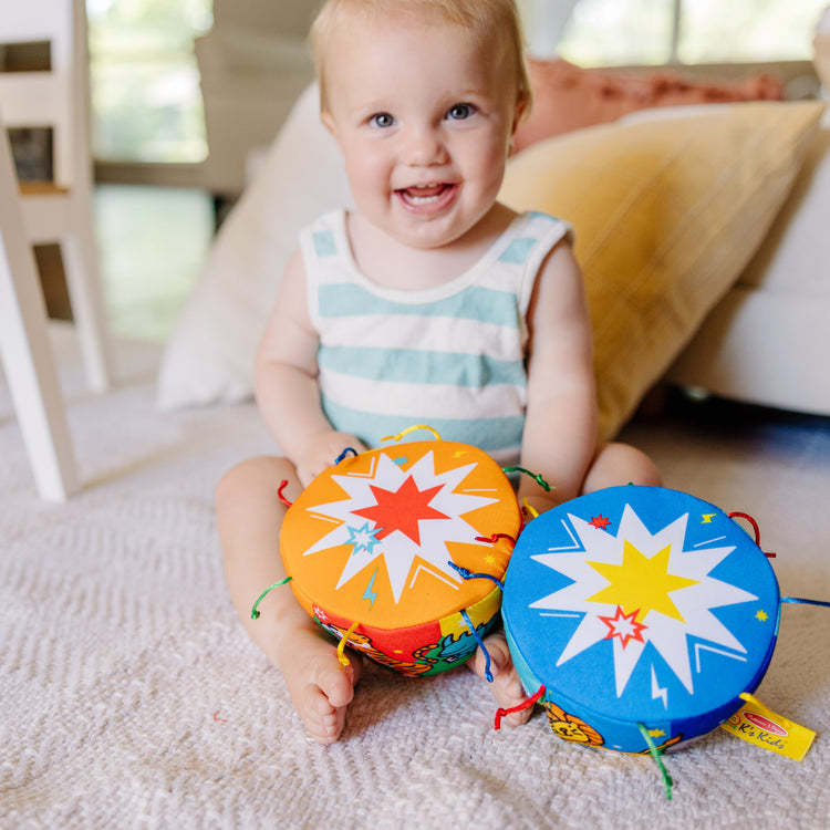 A kid playing with The Melissa & Doug K's Kids Bongo Drums Soft Musical Instrument