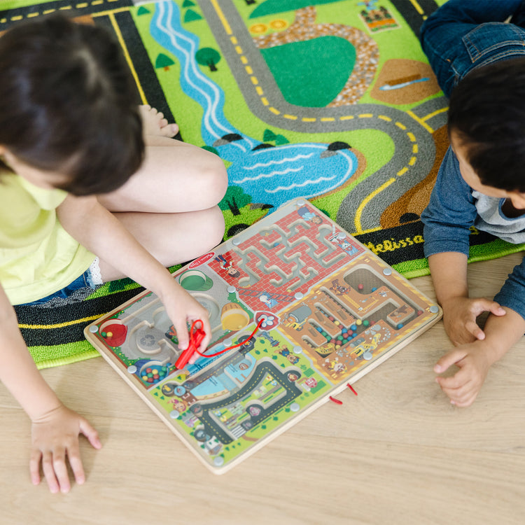 A kid playing with The Melissa & Doug PAW Patrol Wooden 4-in-1 Magnetic Wand Maze Board