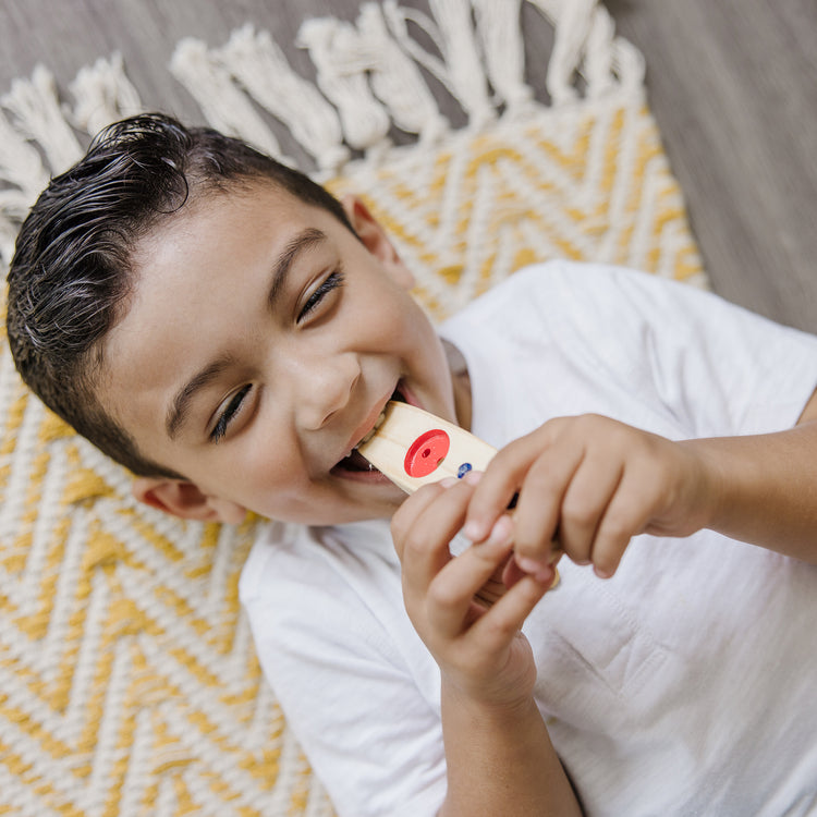 A kid playing with The Melissa & Doug Makin' Music Beginner Wooden Kazoo