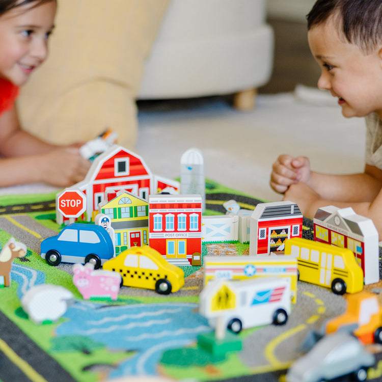 A kid playing with The Melissa & Doug Deluxe Activity Road Rug Play Set with 49 Wooden Vehicles and Play Pieces