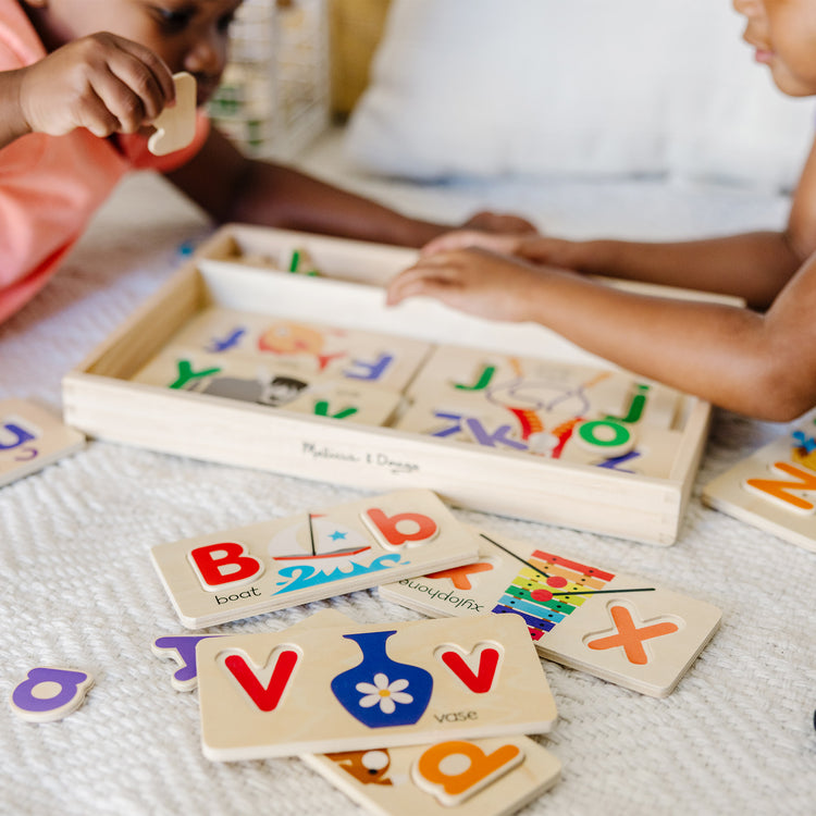 A kid playing with The Melissa & Doug ABC Picture Boards - Educational Toy With 13 Double-Sided Wooden Boards and 52 Letters