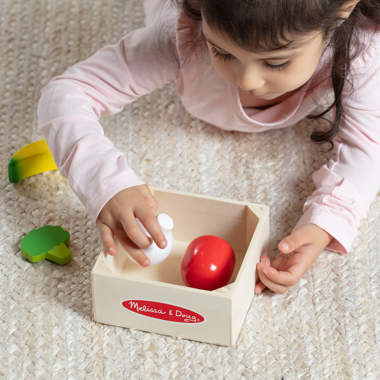 A kid playing with The Melissa & Doug Wooden Food Groups Play Food Set – Produce