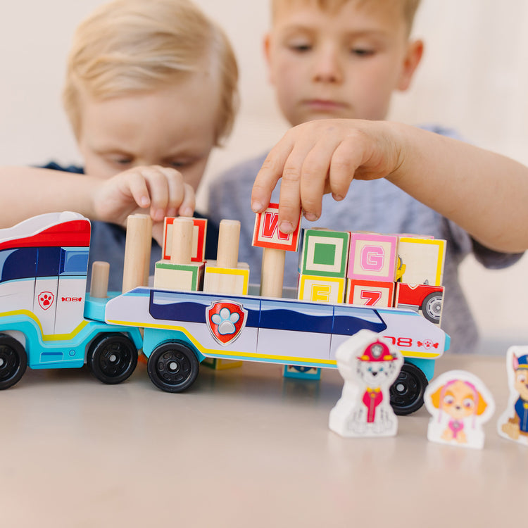 A kid playing with The Melissa & Doug PAW Patrol Wooden ABC Block Truck (33 Pieces)