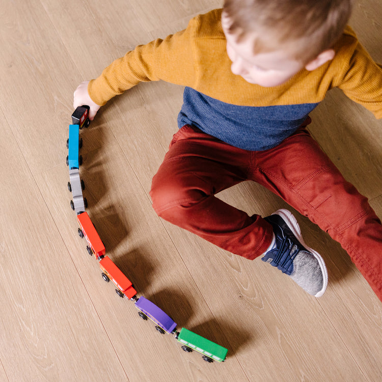 A kid playing with The Melissa & Doug Wooden Magnetic Train Cars - 8 Piece Educational and Skill-Building Wooden Toy for Boys and Girls