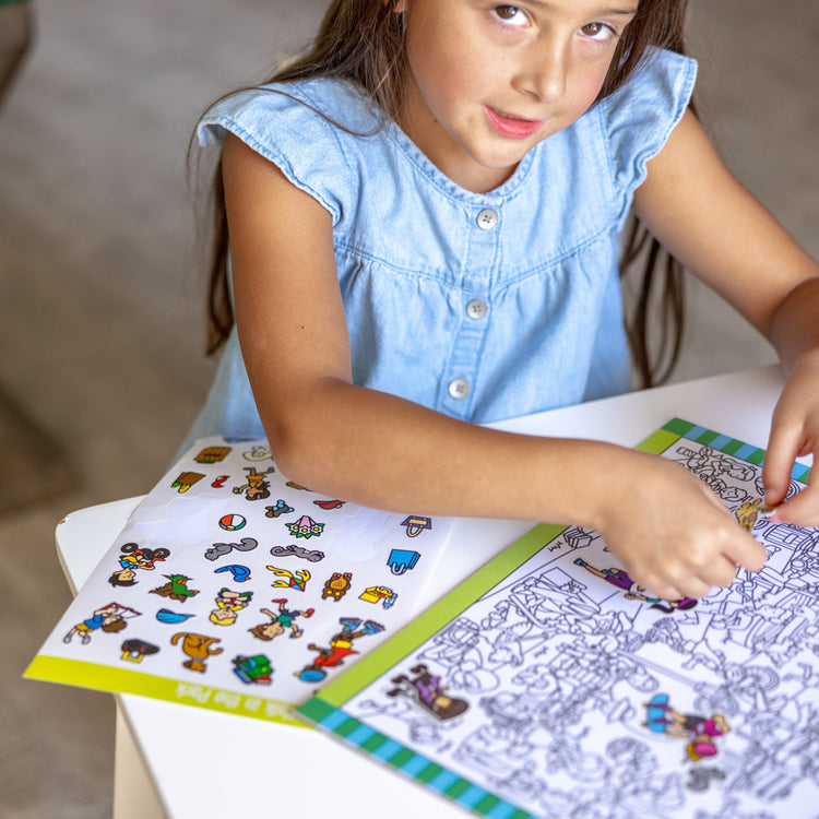 A kid playing with The Melissa & Doug Seek and Find Sticker Pad – Around Town (400+ Stickers, 14 Scenes to Color)