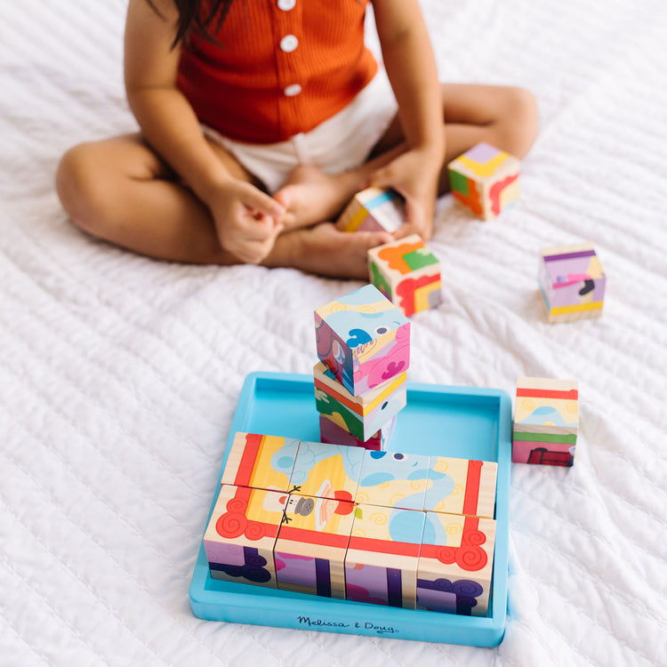 A kid playing with The Melissa & Doug Blue's Clues & You! Wooden Cube Puzzle (16 Pieces)