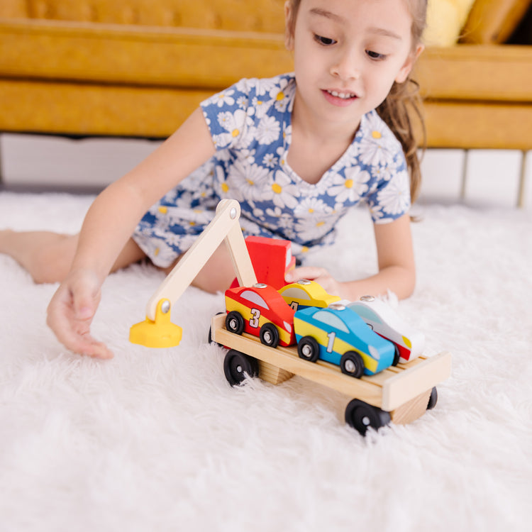 A kid playing with The Melissa & Doug Magnetic Car Loader Wooden Toy Set With 4 Cars and 1 Semi-Trailer Truck