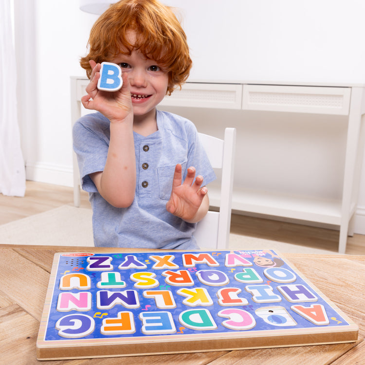 A kid playing with The Melissa & Doug® Ms. Rachel™ Wooden Phonics Alphabet Sound Puzzle, 24-Piece Toddler Toys for Boys and Girls Ages 2+ Years