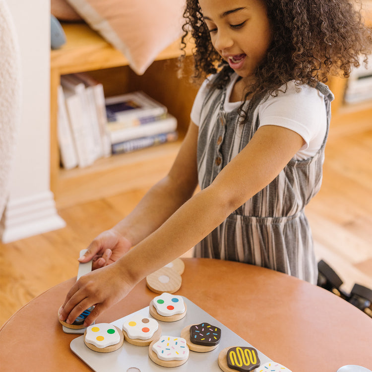 A kid playing with The Melissa & Doug Slice and Bake Wooden Cookie Play Food Set