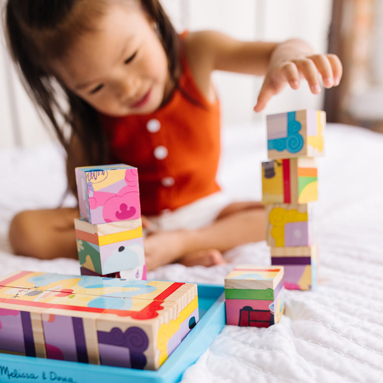 A kid playing with The Melissa & Doug Blue's Clues & You! Wooden Cube Puzzle (16 Pieces)