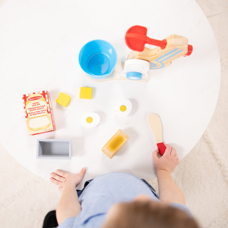 A kid playing with The Melissa & Doug Wooden Make-a-Cake Mixer Set (11 pcs) - Play Food and Kitchen Accessories