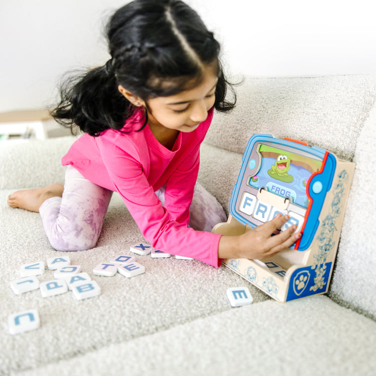 A kid playing with The Melissa & Doug PAW Patrol Wooden See & Spell Pup Pad Game