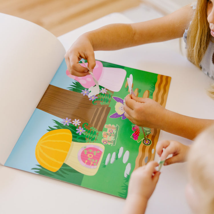 A kid playing with The Melissa & Doug Reusable Sticker Pad: Fairies - 200+ Stickers