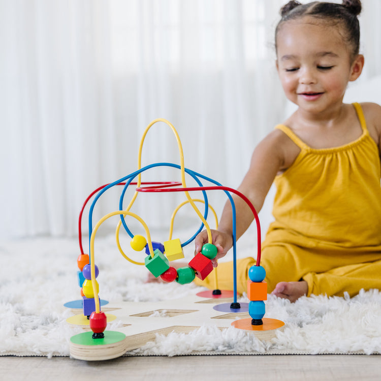 A kid playing with The Melissa & Doug Classic Bead Maze - Wooden Educational Toy