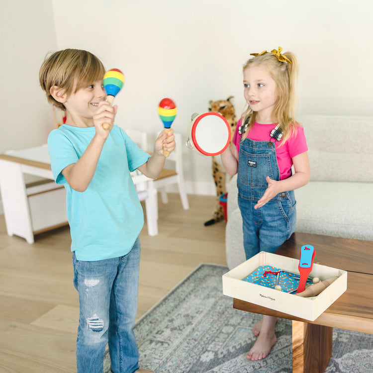 A kid playing with The Melissa & Doug Band-in-a-Box Clap! Clang! Tap! - 10-Piece Musical Instrument Set