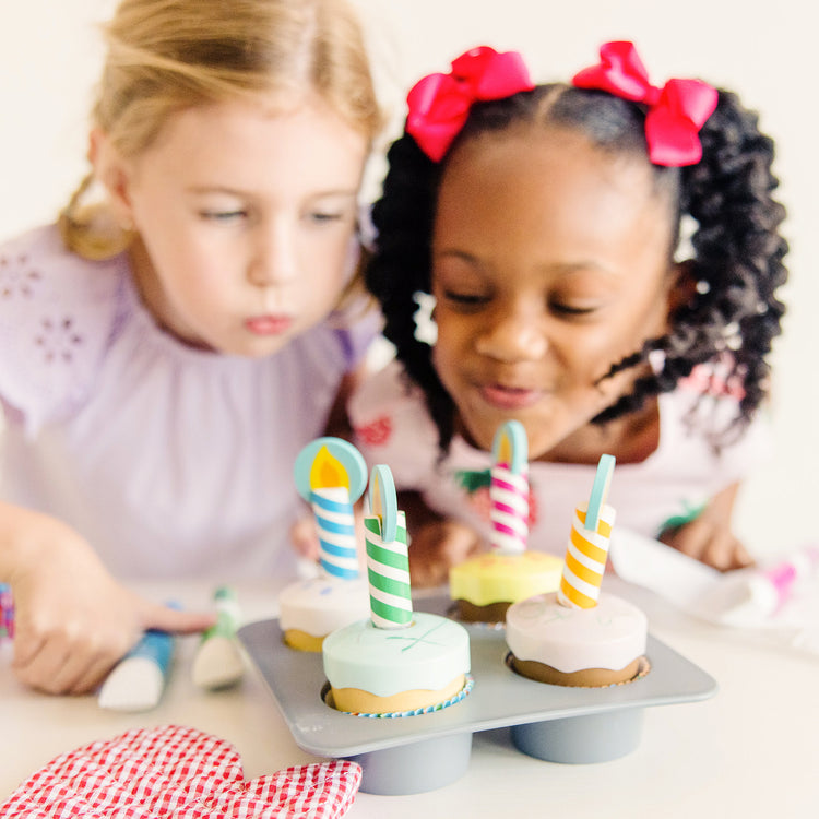 A kid playing with The Melissa & Doug Bake and Decorate Wooden Cupcake Play Food Set